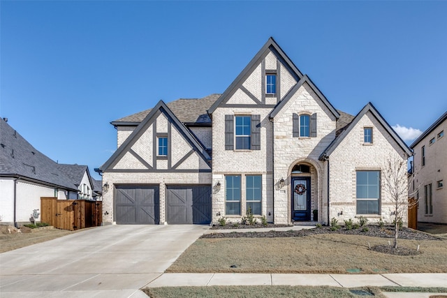 view of front of house with brick siding, a shingled roof, fence, concrete driveway, and a garage