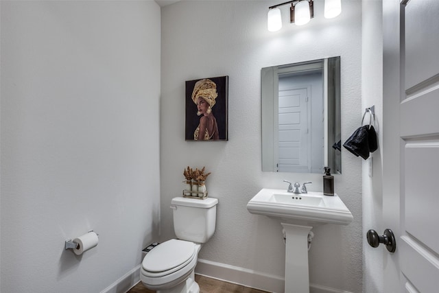 half bathroom with toilet, baseboards, and wood finished floors