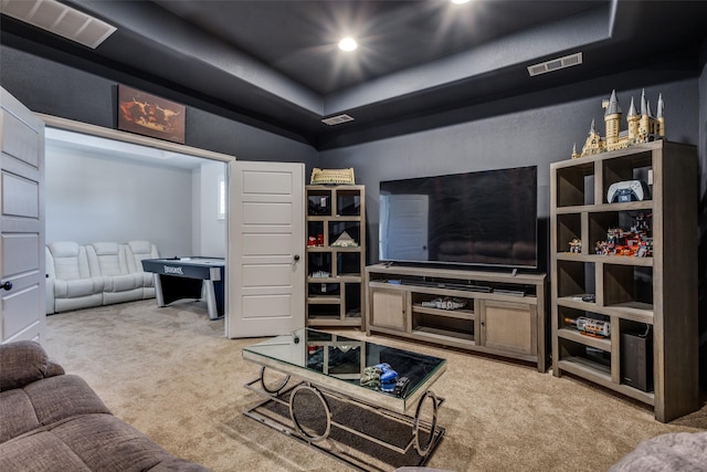 living area with a tray ceiling, carpet flooring, and visible vents