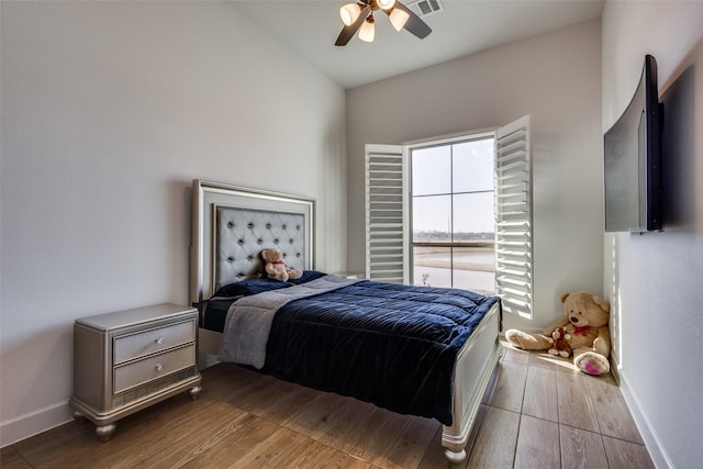 bedroom featuring a ceiling fan, vaulted ceiling, wood finished floors, and baseboards