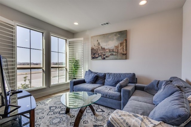 living room with visible vents, recessed lighting, a water view, and wood finished floors