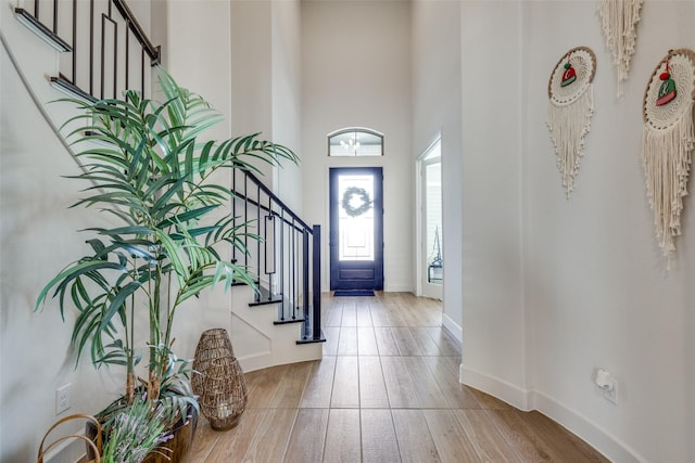 entrance foyer featuring stairway, baseboards, a towering ceiling, and hardwood / wood-style floors