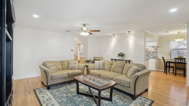 living area featuring recessed lighting, light wood-style flooring, crown molding, and a ceiling fan