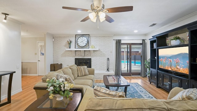 living area with wood finished floors, visible vents, a fireplace, ceiling fan, and ornamental molding