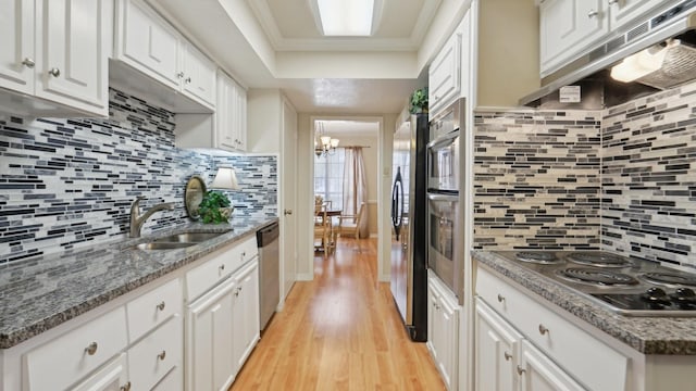 kitchen with a sink, stainless steel appliances, tasteful backsplash, and light wood-style floors