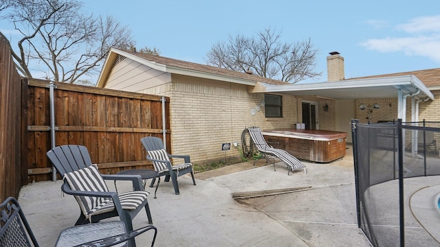 view of patio / terrace with a hot tub and fence