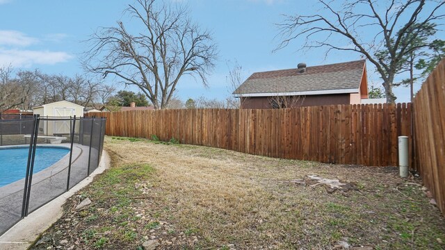 view of yard with a storage unit, a fenced in pool, an outdoor structure, and a fenced backyard