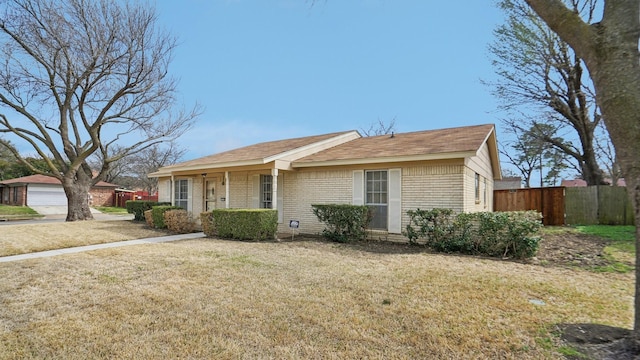 single story home with fence, an outdoor structure, a front yard, a shingled roof, and brick siding