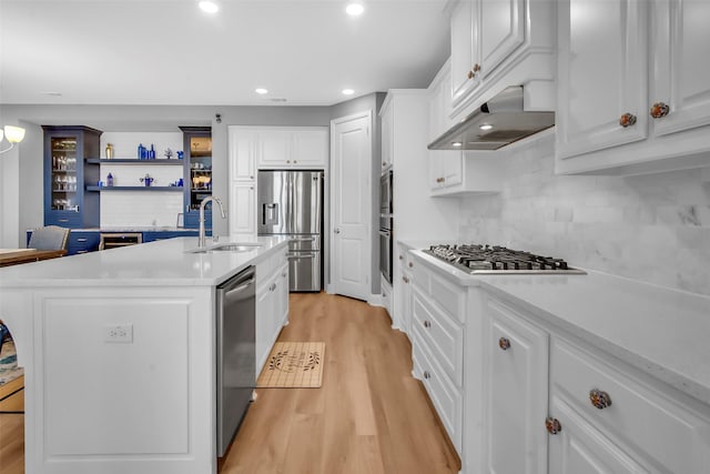 kitchen featuring light wood finished floors, extractor fan, white cabinets, light countertops, and appliances with stainless steel finishes