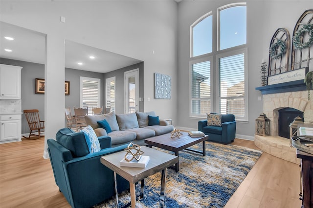 living area featuring a wealth of natural light, a towering ceiling, baseboards, and light wood finished floors