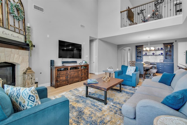 living room featuring a notable chandelier, visible vents, a fireplace, and wood finished floors