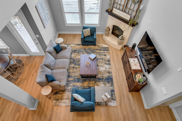 living area with baseboards, wood finished floors, and a fireplace