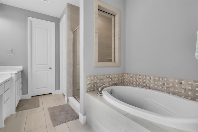 full bathroom with tile patterned flooring, a shower stall, baseboards, a garden tub, and vanity