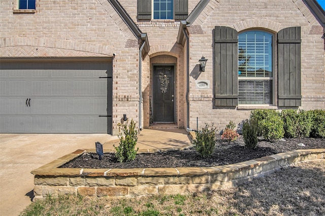 entrance to property with a garage, brick siding, and concrete driveway