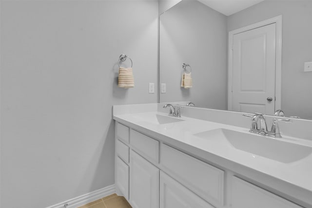 bathroom with a sink, baseboards, double vanity, and tile patterned flooring