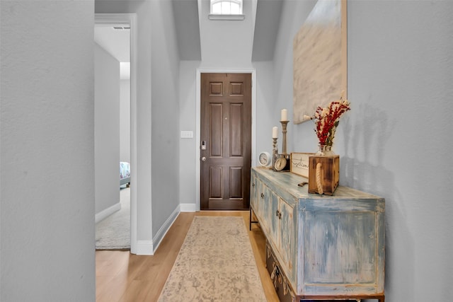 foyer entrance with baseboards and light wood-style floors