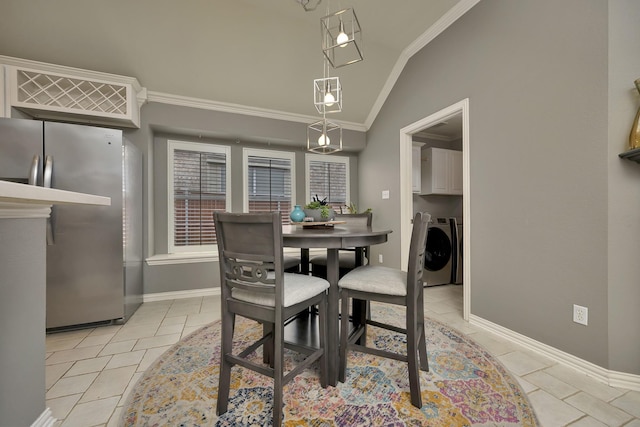 dining room featuring ornamental molding, lofted ceiling, baseboards, washer and clothes dryer, and light tile patterned floors