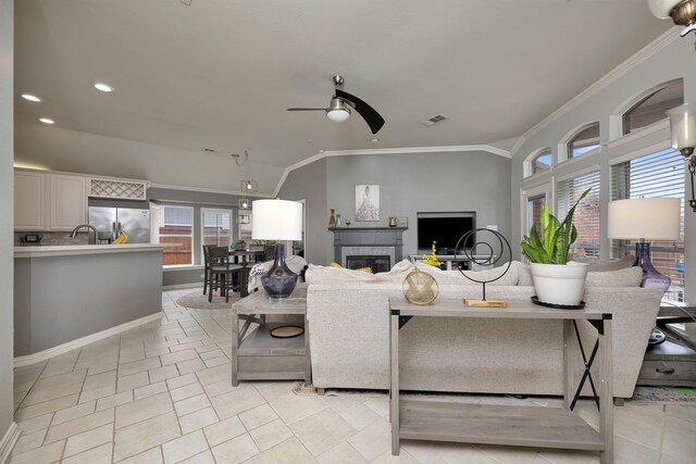 living area featuring crown molding, plenty of natural light, a ceiling fan, and visible vents