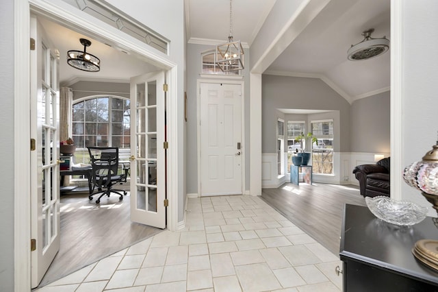 foyer entrance featuring crown molding, a notable chandelier, french doors, and lofted ceiling