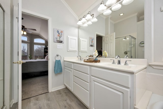ensuite bathroom featuring crown molding, lofted ceiling, wood finished floors, a sink, and a stall shower
