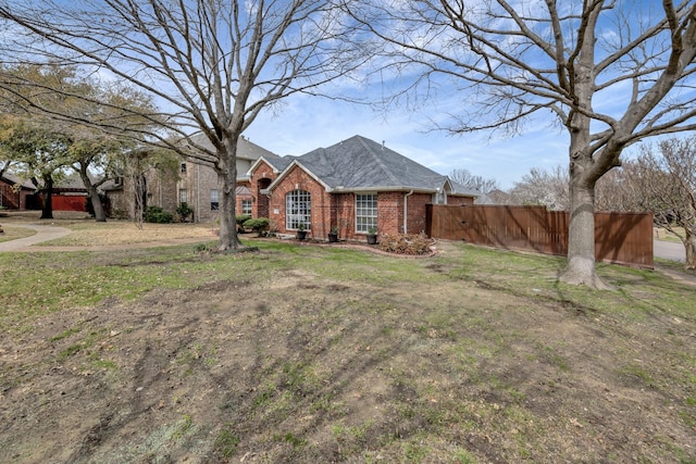 view of front of property featuring brick siding, fence, and roof with shingles