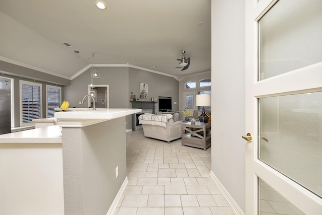 kitchen with light tile patterned flooring, light countertops, baseboards, lofted ceiling, and ornamental molding