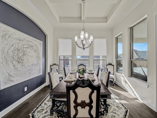 dining space with baseboards, ornamental molding, wood finished floors, a notable chandelier, and a raised ceiling