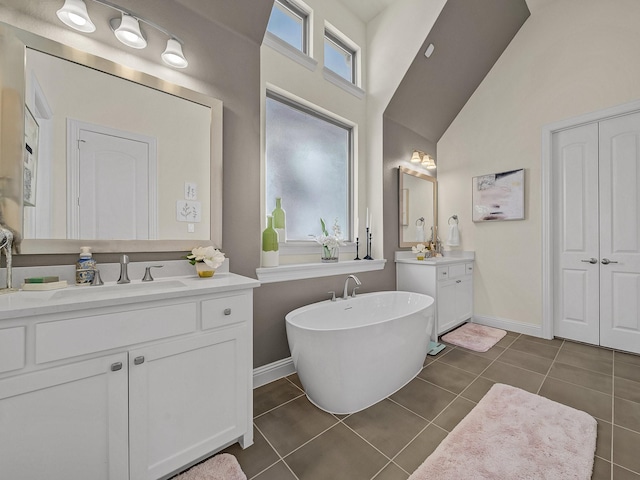 bathroom with baseboards, two vanities, a freestanding bath, a sink, and tile patterned floors