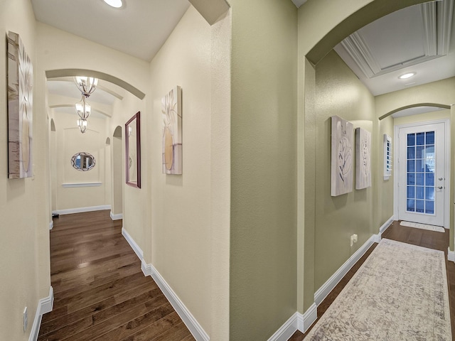 hallway with dark wood finished floors, recessed lighting, arched walkways, and baseboards