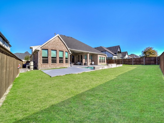 rear view of house with brick siding, a patio area, a lawn, and a fenced backyard