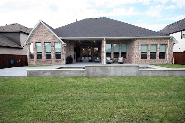 rear view of property with a patio area, a lawn, brick siding, and fence