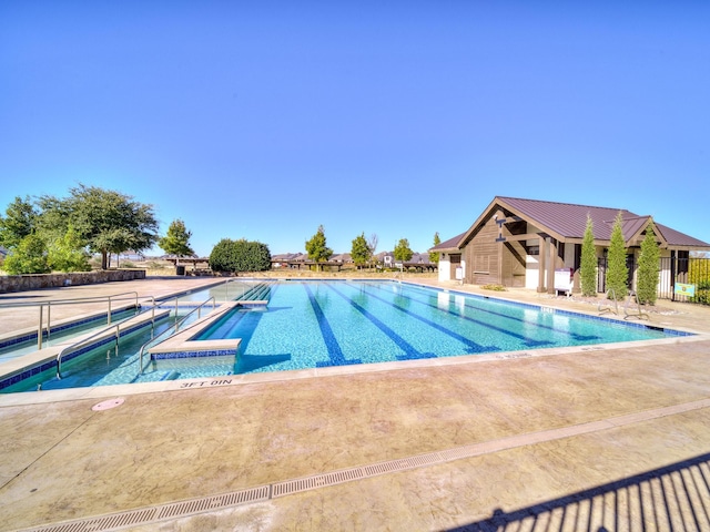 pool with a patio area, fence, and a hot tub