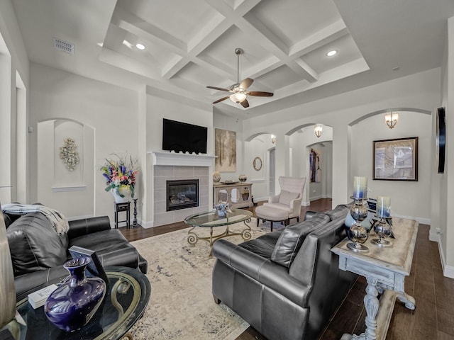 living area featuring visible vents, coffered ceiling, wood finished floors, arched walkways, and ceiling fan