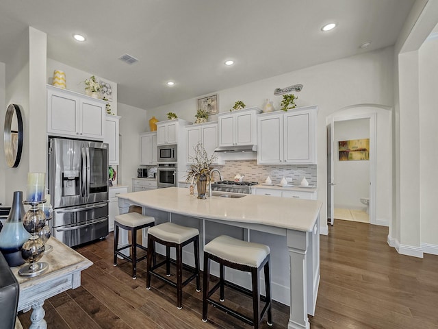 kitchen featuring visible vents, dark wood finished floors, light countertops, arched walkways, and stainless steel appliances