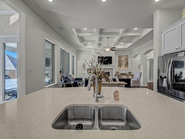 kitchen featuring a sink, coffered ceiling, open floor plan, and stainless steel refrigerator with ice dispenser