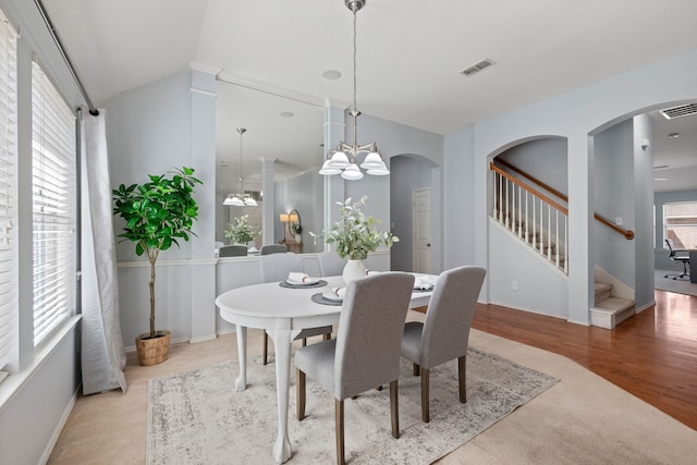 dining area with visible vents, arched walkways, a healthy amount of sunlight, and wood finished floors