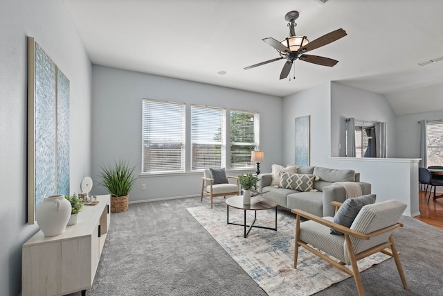 carpeted living area with visible vents, plenty of natural light, baseboards, and a ceiling fan