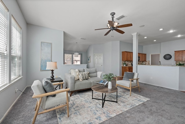 living area with ceiling fan with notable chandelier, carpet, visible vents, and baseboards