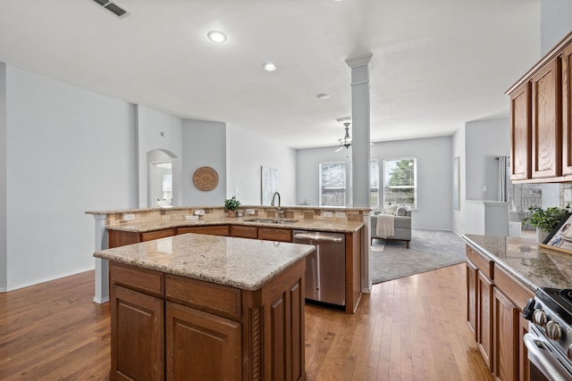 kitchen featuring arched walkways, a sink, stainless steel appliances, hardwood / wood-style flooring, and a center island