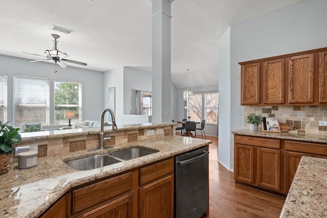 kitchen with visible vents, decorative backsplash, dishwashing machine, brown cabinets, and a sink