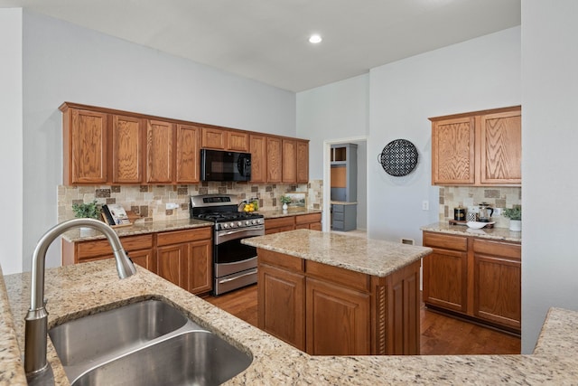 kitchen featuring decorative backsplash, stainless steel gas range, black microwave, and a sink