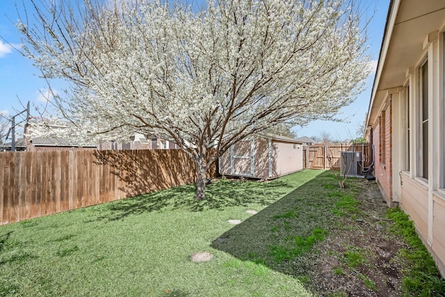 view of yard featuring an outbuilding, central air condition unit, a storage unit, and a fenced backyard