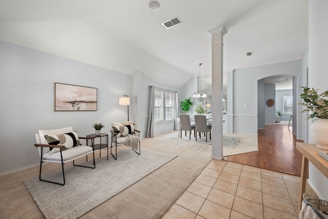 living area with light tile patterned floors, visible vents, arched walkways, vaulted ceiling, and light colored carpet