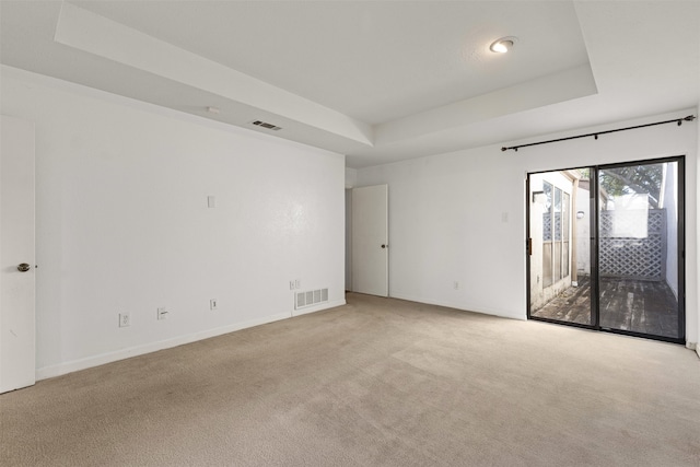 spare room with visible vents, light colored carpet, and a raised ceiling