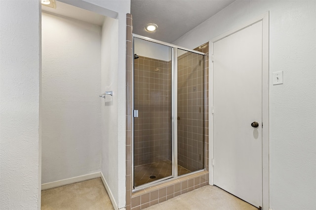 bathroom featuring baseboards, a stall shower, and a textured wall