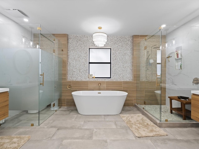 full bathroom featuring vanity, tile walls, a freestanding tub, and a stall shower