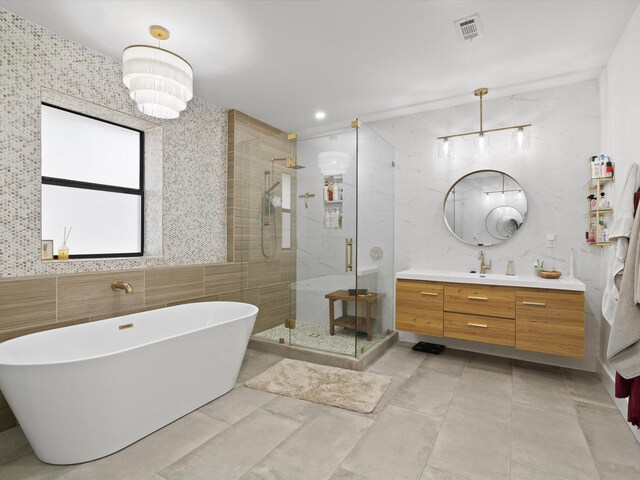 full bath featuring visible vents, a shower stall, vanity, a soaking tub, and tile walls