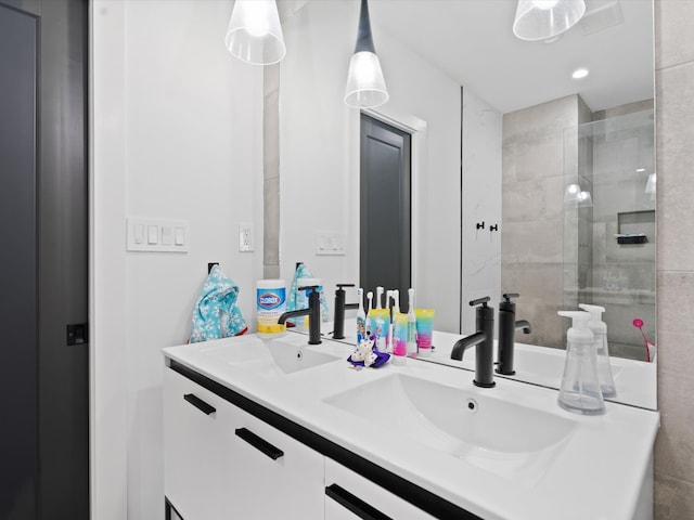 full bathroom featuring double vanity, tiled shower, and a sink