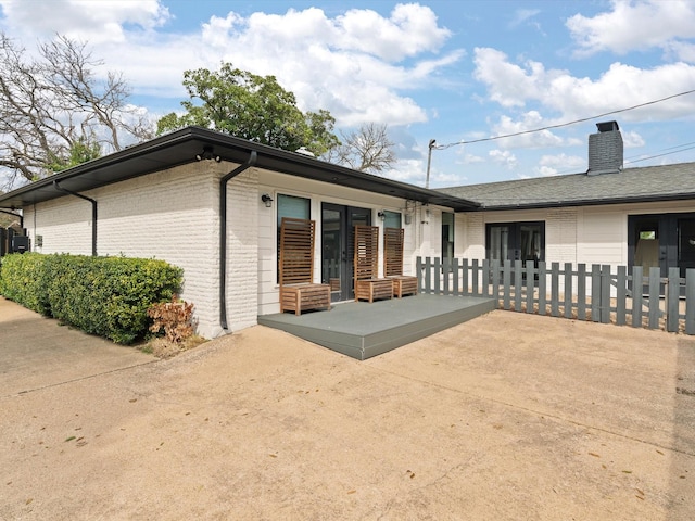 exterior space featuring brick siding, a chimney, and a patio