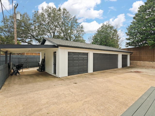 detached garage featuring a carport and fence